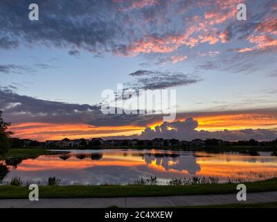 Wunderschöne rosa, orange und blau Sonnenuntergang spiegelt sich auf einem See in einem Vorort. Stockfoto