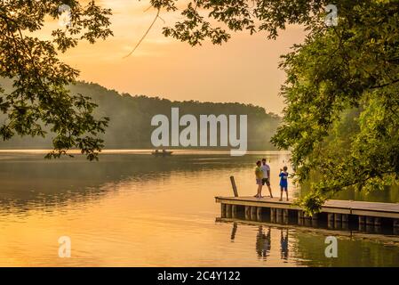 Familienfoto-Moment bei einem feurigen Sonnenuntergang am Ufer des Fort Yargo State Park Campground in Winder, Georgia. (USA) Stockfoto