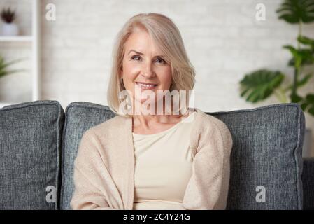 Porträt einer schönen älteren blonden Frau lächelt zu Hause. Stockfoto