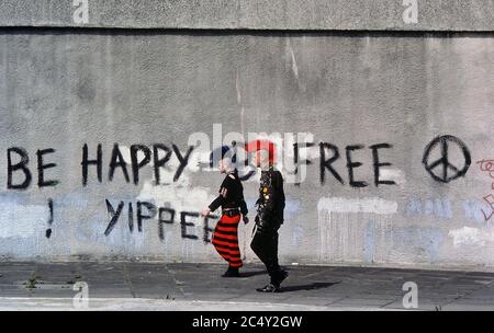 Die Straßenszene eines Teenage Punk Rocker Walking führte einen Slogan CND Graffiti. London England, Großbritannien. Ca. 1980 Stockfoto