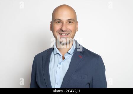 Selbstbewusst gut aussehende Glatze Mann in Jacke lächelt über, während Studio Wand. Stockfoto