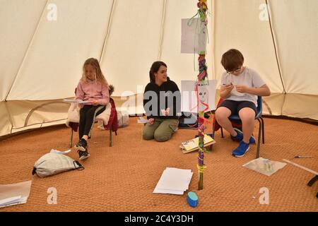 Die Lehrerin Holly Haime unterrichtet die Schüler des fünften Jahrs im Basteln und Basteln, während sie Papierflugzeuge in einem Zelt im Tipi-Stil an der Llanishen Fach Primary School in Cardiff herstellen. Stockfoto