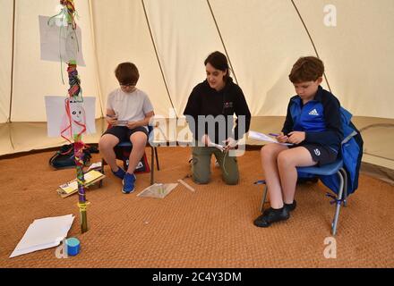 Die Lehrerin Holly Haime unterrichtet die Schüler des fünften Jahrs im Basteln und Basteln, während sie Papierflugzeuge in einem Zelt im Tipi-Stil an der Llanishen Fach Primary School in Cardiff herstellen. Stockfoto