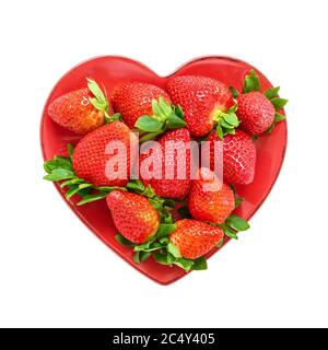 Frische Erdbeeren auf einem roten Teller in Form von Herz isoliert auf weißem Hintergrund mit Clipping Pfad. Draufsicht, Kopierbereich für Text Stockfoto