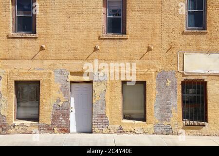 Ein verlassene leeres Geschäftshaus mit einer alten gelben Ziegelsteinmauer Stockfoto