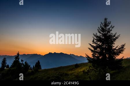 Sonnenuntergang in den Bergen mit Silhouetten von einigen Bäumen Stockfoto