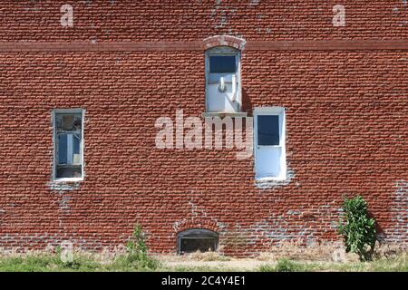 Mehrere alte weiße Vintage Lagerhausfenster auf einem roten Backsteingebäude Stockfoto