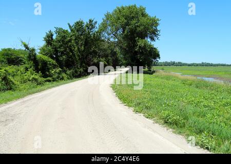 Eine natürliche Schotterstraße führt in schöne Ackerland in der Nähe eines Weideweiher und Lichtung Stockfoto