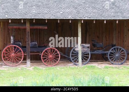 Zwei schöne Vintage Pferdewagen Trap Fahrzeug neben einem rustikalen Stall Stall Gebäude Stockfoto
