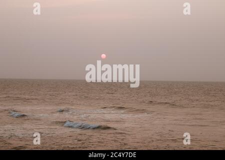 Ein Vollmond leuchtet rosa, wie es über die steigt meer in der Nähe von Cartagena Stockfoto