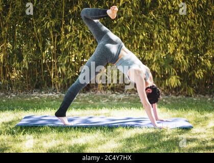 Junges Mädchen tun Yoga im Garten mit Matte Stockfoto