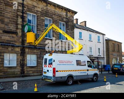 Mann auf einem hydraulischen Hebezeug Durchführung einer Reparatur an der Uhr auf dem Rathaus Stokesley North Yorkshire Stockfoto