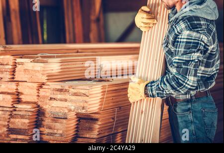 Arbeiter, Der Bündel Von Holz Aus Holzplanken Im Baustofflager Abholt. Stockfoto