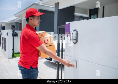 Asiatische Lieferung Soldaten tragen eine rote Uniform mit einer roten Kappe Handhabung Kartons, um den Kunden vor dem Haus zu geben und klicken Sie auf die Do Stockfoto
