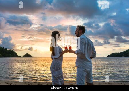 Paar in tropischen Urlaub mit Getränken Toasten am Strand am Meer Stockfoto