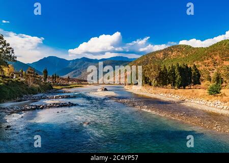 Mo Chhu River an einem schönen sonnigen Tag, Punakha, Bhutan. Blick von der hölzernen Freischwinger Brücke in der Nähe Punakha Dzong zum Fluss, Häuser der Stadt Punakha und ihm Stockfoto