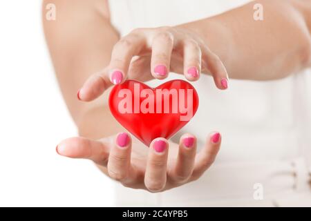 Save Love oder Healthcare Konzept. Zwei Frauenhänden schützen das Rote Herz auf weißem Hintergrund. Stockfoto