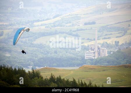 Paragliding vor dem Mam Tor Hügel bei Castleton im High Peak von Derbyshire, England, eingerahmt von den Zementwerken Stockfoto