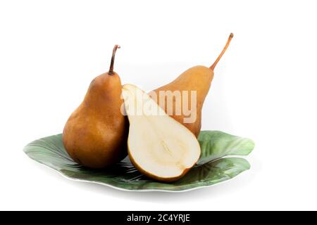 Eine Gruppe von Bosc Birnen auf einem grünen Blatt förmigen Teller mit einer Birne in der Hälfte isoliert auf weiß geschnitten Stockfoto