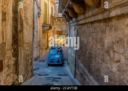 Touristen auf einer Tour im alten Fiats 500 durch die engen Gassen von Modica auf der Insel Sizilien in Italien. Stockfoto