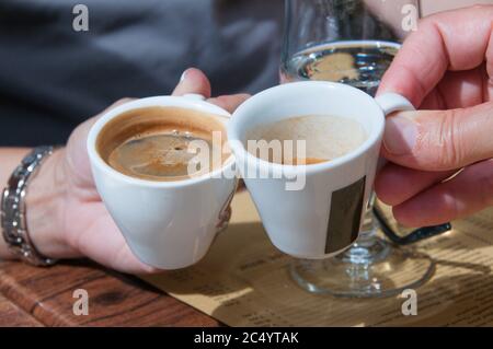 Nahaufnahme eines Mannes und einer Frau, die Espressotassen halten. Nur Hände und Tassen. Stockfoto