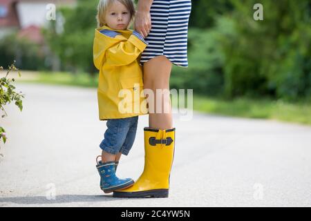 Mutter und Kleinkind Kind, Junge, spielen im Regen, Stiefel und Regenmäntel tragen Stockfoto
