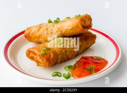 Frühlingsrollen auf einem Teller serviert mit süßen Chili-Sauce isoliert auf weißem Hintergrund. Stockfoto