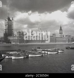 1950er Jahre, historisch, Blick von der anderen Seite der Themse auf den Palace of Westminster, London, der Treffpunkt für die beiden Häuser des britischen Parlaments, die Houses of Commons und die Houses of Lords, England, Großbritannien. Ein prachtvoller viktorianischer gotischer Palast, der von Sir Charles Barry und A. W Pugin entworfen wurde und die mittelalterlichen parlamentsgebäude ersetzt, ist ein ikonisches Symbol Londons und Großbritanniens. Stockfoto