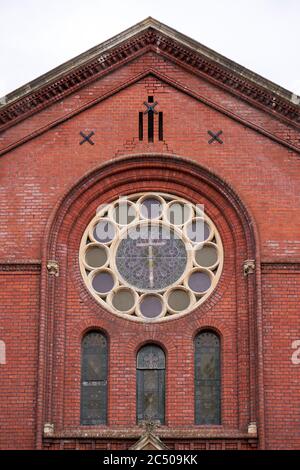 Großes rundes Fenster in rote Backsteinmauer einer Kirche gesetzt Stockfoto