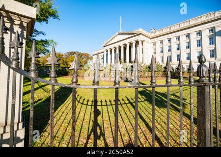 Washington DC USA - Oktober 28 2014; schmiedeeiserner Zaun und Schatten auf Rasen vor dem South End Neoklassisches Department of Treasury Building, Washingto Stockfoto