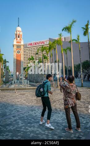 Ein männlicher und weiblicher Tourist, der Fotos vom Kowloon Canton Railway Clock Tower in Kowloon Tsim Sha Tsui, Hongkong macht. Stockfoto