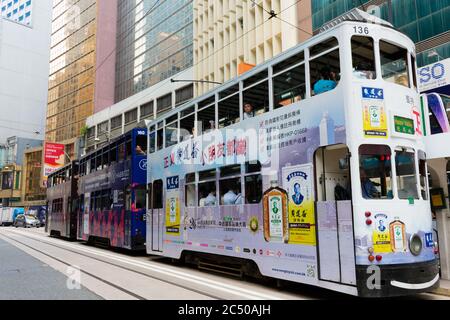 Elektrische Straßenbahnen im Central District. Hong Kong Island mit bunten Werbungen bedeckt und von Wolkenkratzern umgeben. Stockfoto