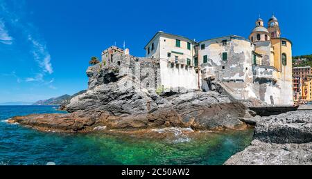 Panorama der mittelalterlichen Festung und Basilika auf den Felsen im Mittelmeer unter blauem Himmel in der kleinen Stadt Camogli, Ligurien, Italien. Stockfoto