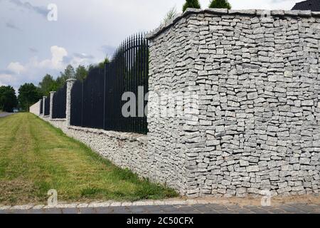 Zaun. Beeindruckender und sehr langlebiger Zaun des Grundstücks aus gespaltenen Granit. Stockfoto