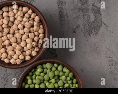 Grüne Erbsen und Kichererbsen in einem braunen Topf. Der graue Hintergrund. Stockfoto