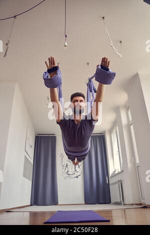 Schöner bärtiger Mann, der im Studio Luftyoga praktiziert Stockfoto