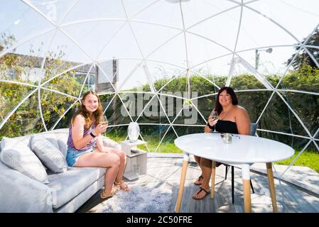 Abbie Copping und (R) Sophie Green in einem der klimatisierten Außenspeisesoots, die für die soziale Distanz der Gäste im The Barn Restaurant, Terrington St. John, Norfolk, konzipiert wurden. Stockfoto