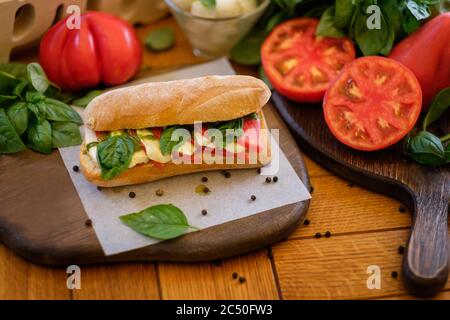 Leckere italienische Caprese auf Ciabatta Sandwich mit Ingridien herumliegen - Tomaten, Bazil und mazzarella. Konzept der traditionellen italienischen Küche recip Stockfoto