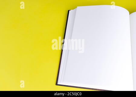 Modell für leere Buchbroschüre mit leeren Seiten und Kopierbereich auf gelbem Hintergrund. Draufsicht. Stockfoto
