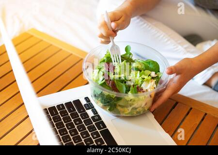 Büroangestellter isst auf der Arbeit einen Salat zum Mitnehmen. Das Konzept der gesunden Ernährung am Arbeitsplatz. Diät am Arbeitsplatz. Stockfoto