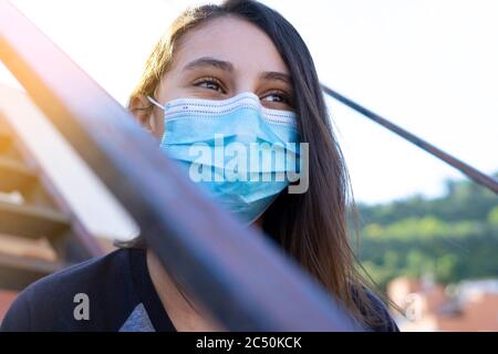 Frau mit Maske lächelnd und Blick geradeaus. Konzept der Frau mit Maske in der Stadt. Selektiver Fokus. Stockfoto