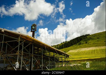 Die kleine Kirche der Madonna della Cona, in der Nähe von Castelluccio di Norcia, umgeben von Verstärkungsstrukturen, um Erdbebenschäden zu beheben. Stockfoto