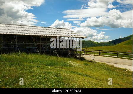 Die kleine Kirche der Madonna della Cona, in der Nähe von Castelluccio di Norcia, umgeben von Verstärkungsstrukturen, um Erdbebenschäden zu beheben. Stockfoto