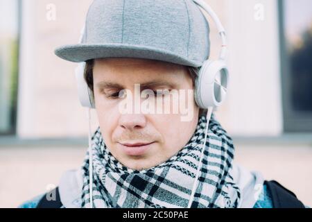 Ein Kaukasischer Mann in einer grauen Mütze ist traurig, wenn er Musik hört. Stockfoto