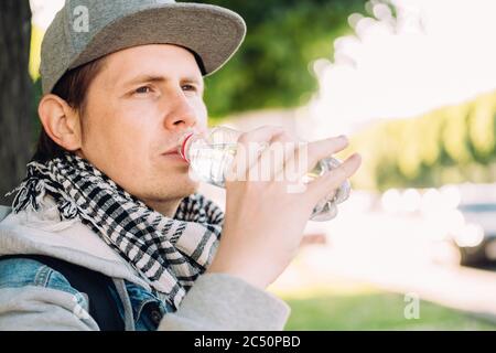 Der Kaukasusmann trinkt Mineralwasser aus einer Plastikflasche. Stockfoto