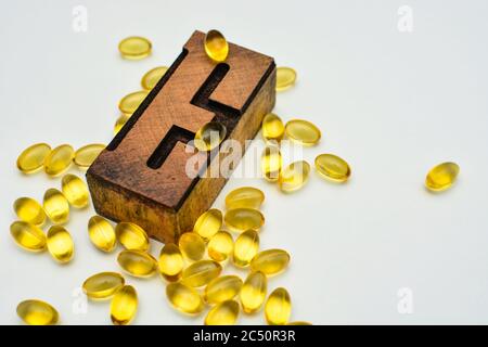 Vitamin E weiche Gel Kapseln und Holz typografische Buchstaben E. Gesundheitswesen und Immunität Unterstützung Konzept. Stockfoto