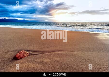 Eine bunte Ozean Sonnenuntergang Landschaft als Welle kommt an die Strandküste Stockfoto