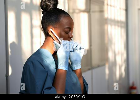 Müde weibliche afrikanische Krankenschwester Ausziehen Gesichtsmaske fühlen Stress Erleichterung im Krankenhaus. Stockfoto