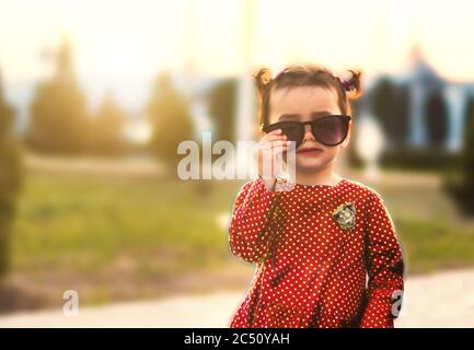 Stilvolle Mädchen in einem roten Kleid und Sonnenbrille Stockfoto