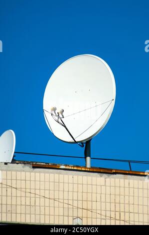 Satellitenschüssel auf dem alten Dach gegen den blauen Himmel Stockfoto